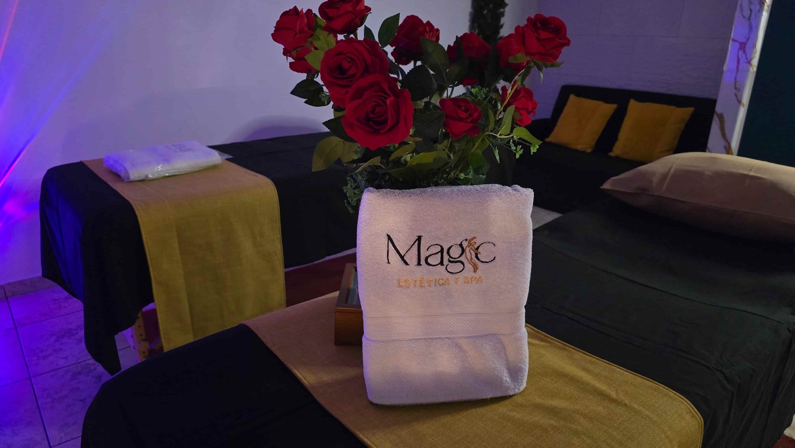 Cabina de Magic Estética y Spa preparada con camillas, flores y toalla de la marca.